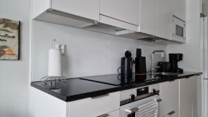a kitchen with white cabinets and a black counter top at Cozy Apartment near Aura river in Turku