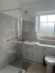 uma casa de banho com um lavatório, um WC e uma janela. em Anchors Away by the Sea em Harwich