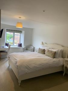 Un dormitorio con una gran cama blanca y una ventana en The Heritage Bed and Breakfast en Weymouth