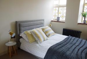 a bedroom with a bed with a blue blanket and two windows at Studio 4- 6 Norwich City Centre Apartment in Norwich