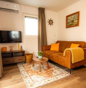 a living room with a brown couch and a tv at Chalet Sjaantje in Egmond aan den Hoef