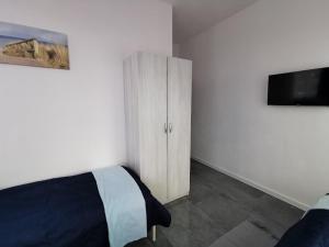 a bedroom with a bed and a cabinet with a television at Plażowa 2 in Rowy