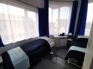 a bedroom with two beds and blue curtains and windows at Plażowa 2 in Rowy