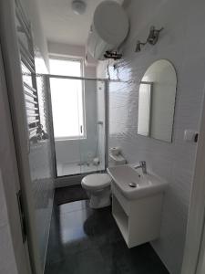 a white bathroom with a toilet and a sink at Plażowa 2 in Rowy
