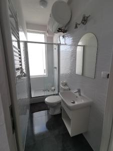 a white bathroom with a toilet and a sink at Plażowa 2 in Rowy +2 photos