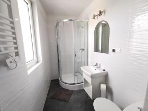 La salle de bains blanche est pourvue d'une douche et d'un lavabo. dans l'établissement Plażowa 2, à Rowy