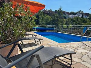 einen Pool mit 2 Stühlen und einem Sonnenschirm in der Unterkunft Pension am Weinberg Bed & Breakfast in Mainstockheim
