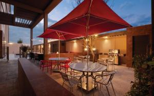 een patio met tafels en stoelen en rode parasols bij Home2 Suites By Hilton Winter Garden in Orlando