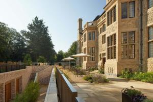 ein Backsteingebäude mit Tischen und Sonnenschirmen im Innenhof in der Unterkunft Rhodes House, Oxford in Oxford