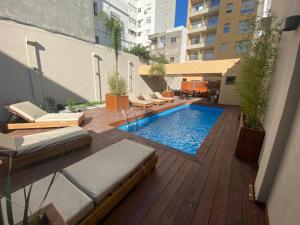 uma piscina com espreguiçadeiras num deque de madeira em Excelente apto 1 dorm completo em Montevidéu