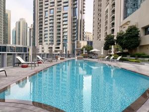 a large blue swimming pool with chairs and buildings at 3 BEDROOM APARTMENT ON MONTHLY RENT in Dubai