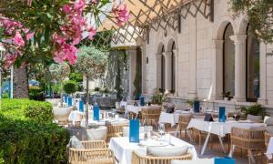 a restaurant with tables and chairs and pink flowers at Aminess Younique Korcula Heritage Hotel in Korčula