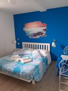 a blue bedroom with a bed and a painting on the wall at B&B Villa Jasiga in Fregene
