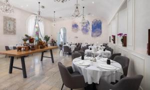 a dining room with tables and chairs and chandeliers at Aminess Younique Korcula Heritage Hotel in Korčula