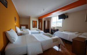 une chambre d'hôtel avec trois lits et un canapé dans l'établissement Hotel Balcones Plaza, à Cajamarca