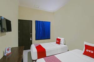 ein Hotelzimmer mit 2 Betten und einem TV in der Unterkunft Super OYO 92437 Wahidin Guesthouse in Pekalongan