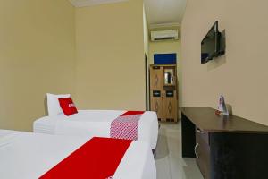 ein Hotelzimmer mit 2 Betten und einem TV in der Unterkunft Super OYO 92437 Wahidin Guesthouse in Pekalongan