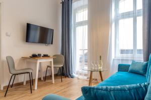ein Wohnzimmer mit einem blauen Sofa und einem Tisch in der Unterkunft Chill Apartments Central Station Katowice in Kattowitz