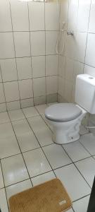 a bathroom with a toilet in a white tiled room at Casa Da Rua Da Pedra in São José dos Campos