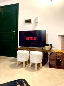 a living room with a tv and two white chairs at Baita Campo Felice in Collimento