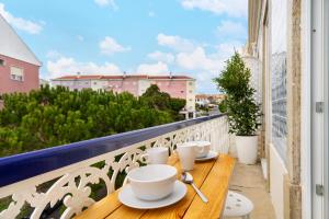 a wooden table with cups and saucers on a balcony at WHome Beato Premium River View in Quiet Area in Lisbon