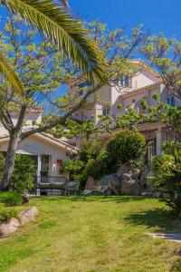 una grande casa bianca con una palma nel cortile di Résidence Les Toits de Santa Giulia a Porto Vecchio