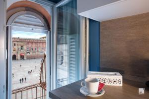 a cup of coffee sitting on a table next to a window at Urbanicooh Asinelli - Balcony on Piazza Maggiore in Bologna