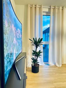 a room with a tv and a plant in front of a window at AMAO-Grey I 86qm I KingSizeBetten I Netflix I Balkon I Parkplatz I EuropaPark in Rheinhausen