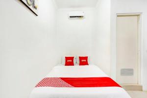 een witte slaapkamer met een wit bed met rode kussens bij SUPER OYO 3702 Homestay Bougenville Syariah in Lamongan
