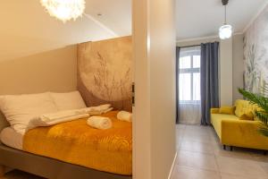 ein Schlafzimmer mit einem Bett und einem gelben Sofa in der Unterkunft Chill Apartments Central Station Katowice in Kattowitz