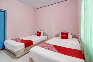 twee bedden in een kamer met rode kussens erop bij OYO 92761 Hotel Sendang Asri in Wonogiri