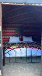 a bed in a room with a wall at Celestial Camp Wadi Rum in Wadi Rum