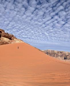 a person standing on a sand dune in the desert at Celestial Camp Wadi Rum in Wadi Rum