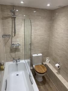 La salle de bains est pourvue de toilettes et d'une baignoire avec douche. dans l'établissement The Heritage Bed and Breakfast, à Weymouth