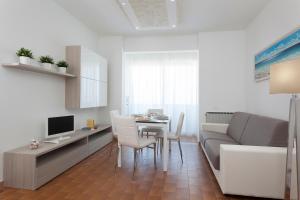 un soggiorno con divano e tavolo con sedie di Residenza Levante a Riccione