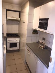uma pequena cozinha com armários brancos e um fogão em Arriendo Departamento em Santiago