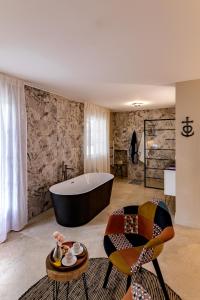 uma casa de banho com uma banheira, 2 cadeiras e uma mesa em Mas de Ceoulet - Villa de Luxe en Camargue em Arles