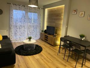 a living room with a table and a television at Apartamenty Centrum + parking in Toruń