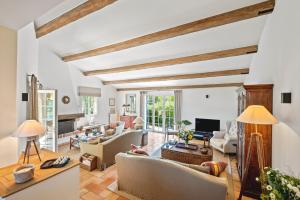 una sala de estar con paredes blancas y vigas de madera. en Villa Quercia, en Fréjus