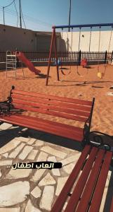 a wooden bench in a playground with swings at شاليه أمي لولوة in Az Zulfi