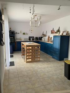 Fontenay-sur-VègreにあるGite de Groupe Aux Instants Partagésのキッチン(青いキャビネット、木製テーブル付)