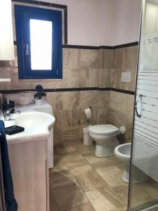 uma casa de banho com um lavatório, um WC e uma janela. em Casa Caterina em Orosei