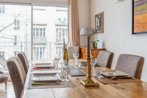 stół jadalny z krzesłami i duże okno w obiekcie Spacious apartment with balcony in Paris - Welkeys w Paryżu