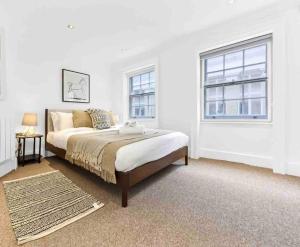 a white bedroom with a bed and two windows at Piccadilly House in London