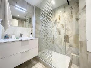 La salle de bains est pourvue d'un lavabo blanc et d'une douche. dans l'établissement Deauville Studio - Face mer, à Deauville