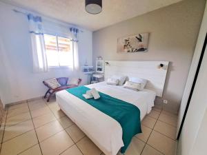 ein Schlafzimmer mit einem großen weißen Bett und einem Stuhl in der Unterkunft La Villa Camael in Le Tampon