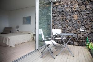 ein Schlafzimmer mit einer Steinmauer, einem Tisch und einem Bett in der Unterkunft Casa Neptuno-Lagoa São Miguel in Lagoa
