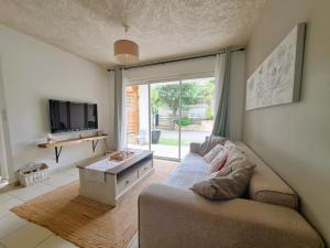ein Wohnzimmer mit einem Sofa und einem TV in der Unterkunft La Villa Camael in Le Tampon