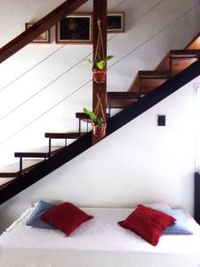 a bed with two red pillows in a room with stairs at Alma Cabaña de Mar in San Eduardo del Mar