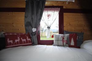 1 dormitorio con cama con almohadas y ventana en La roulotte belle fleur, en Saint-Nabord